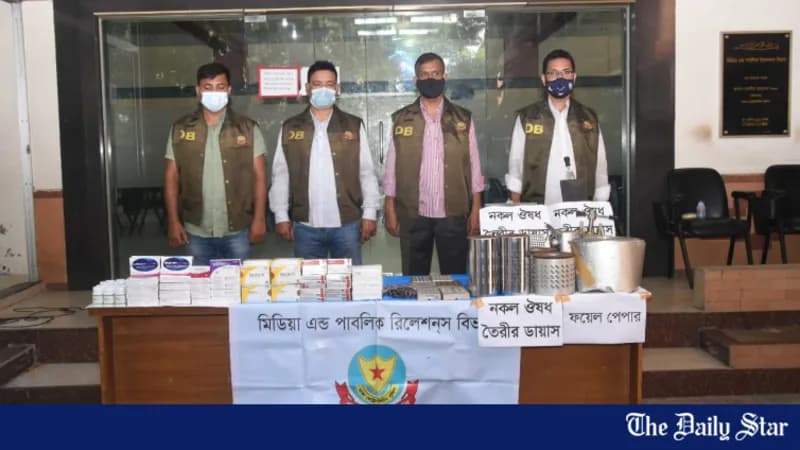 Detective Branch officers standing behind a table stacked with boxes of seized counterfeit medicine.